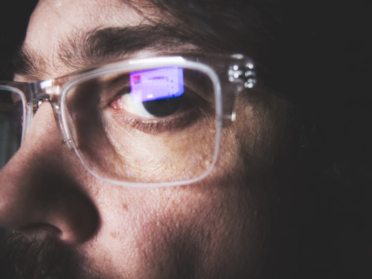 Close-up of an eye behind clear lenses reflecting a screen