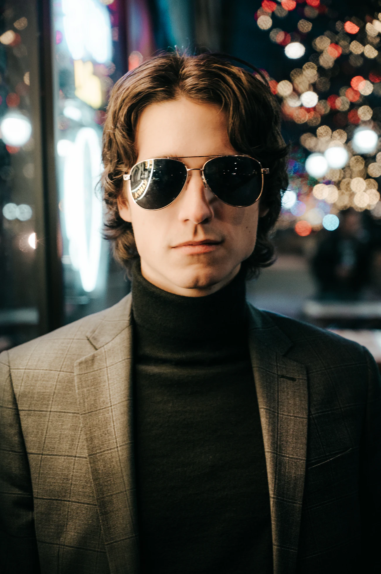 Man in a turtleneck and tweed jacket wearing gold aviator sunglasses