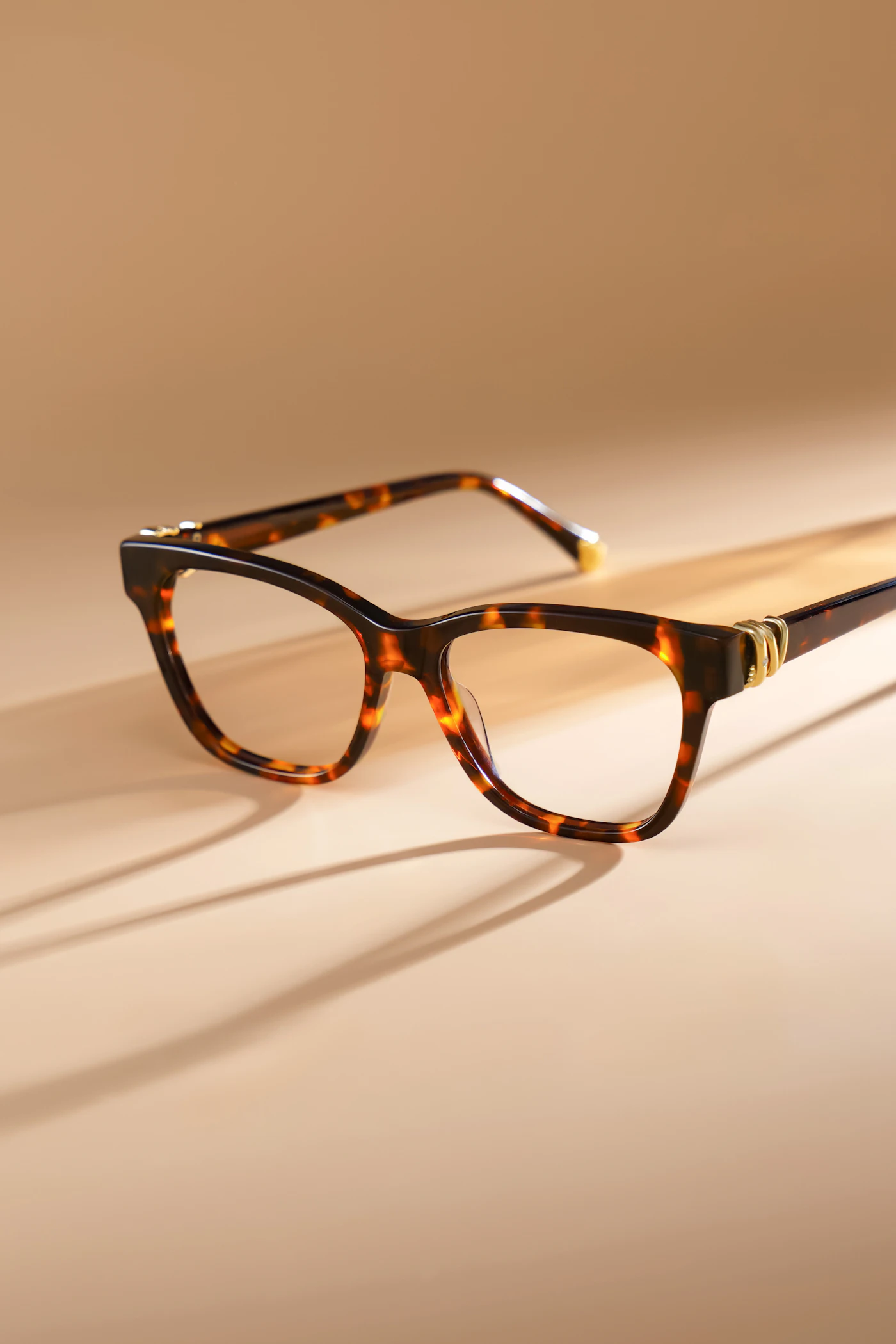 Tortoiseshell acetate eyeglasses on a warm neutral backdrop