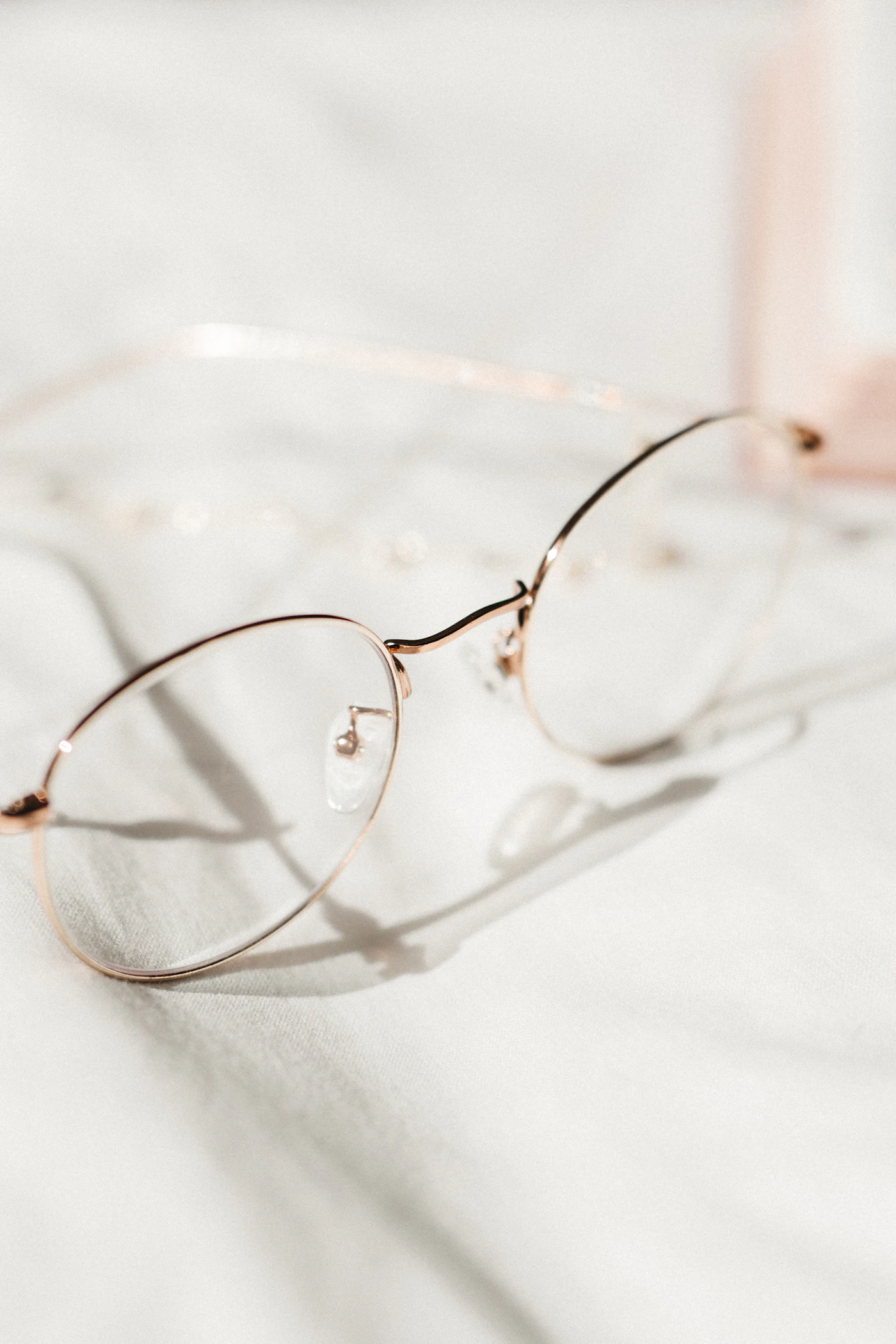 Thin rose-gold titanium eyeglasses on linen
