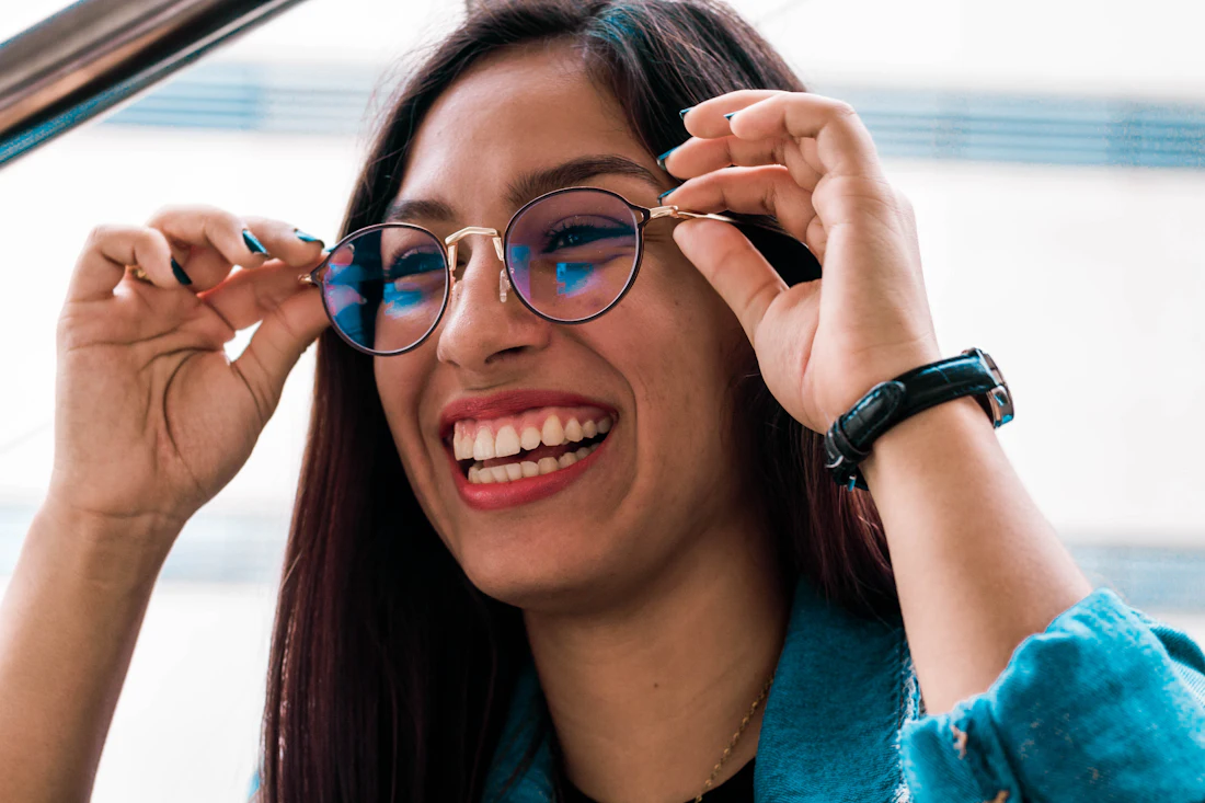 Woman smiling while adjusting her black eyeglasses