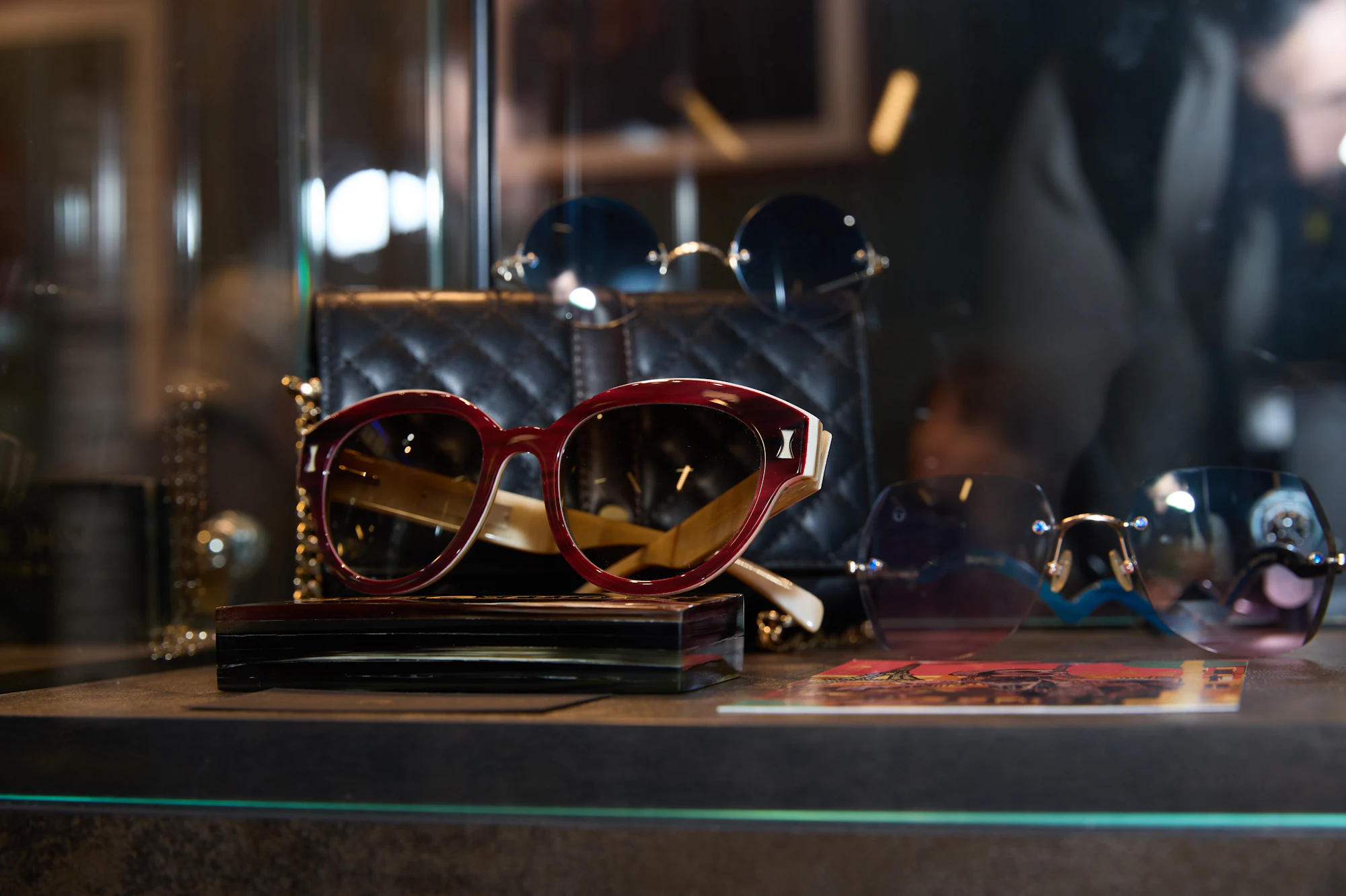 Luxury sunglasses and a quilted handbag displayed in a softly lit boutique cabinet