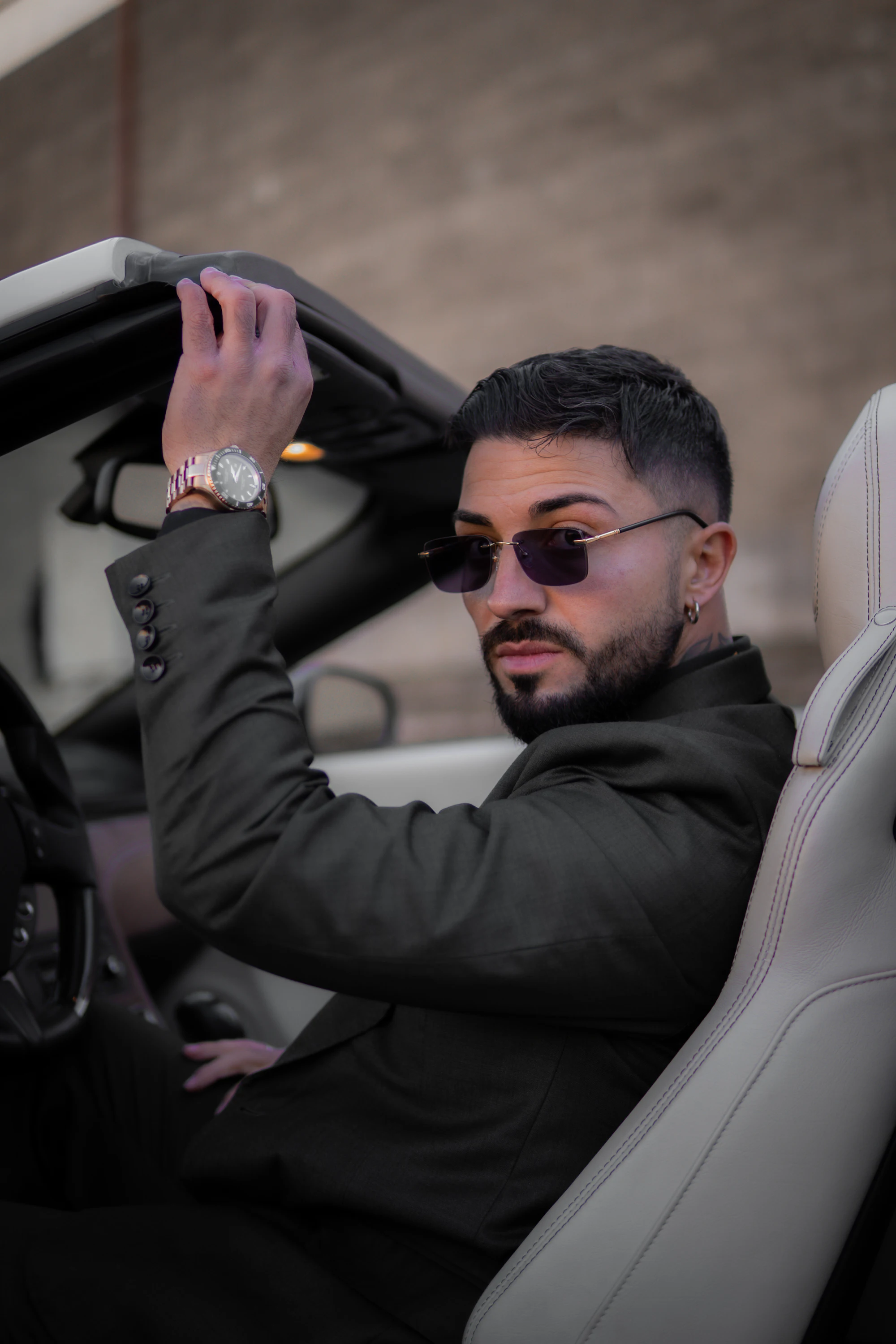 Man in a black suit wearing sunglasses in a convertible